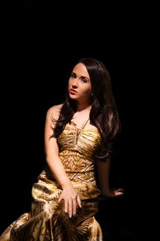 pretty brunette woman in sophisticated evening gown on black background