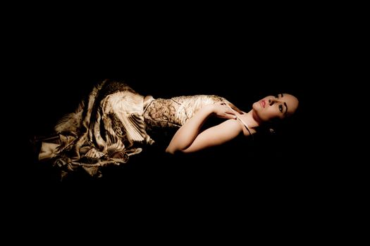 brunette woman in evening gown lying down on black background