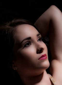 low key portrait of beautiful dark haired woman on black background