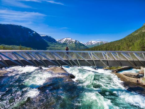 Girl standing on bridge above waterfall Likholefossen on Gaularfjellet tourist national road in Norway