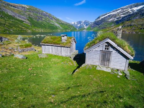 Old norwegian huts by picturesque lake surrounded by mountains in Gaularfjellet mountain pass in Norway
