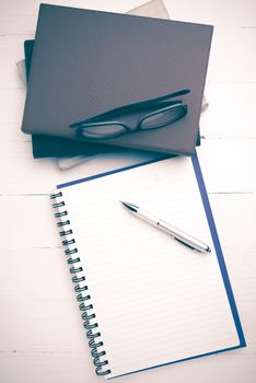 notepad with stack of book on white table view from above vintage style