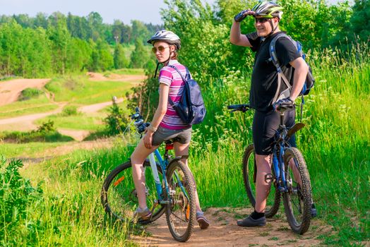 couple athletes on the mountain bike resting on a hill