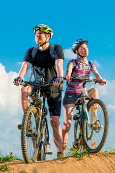 Young cyclists on mountain covered rays of sun