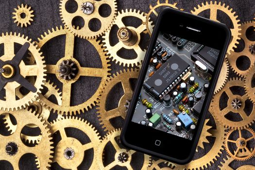 Old and New Technology - Old clockwork cogs and gears and a smartphone with digital technology