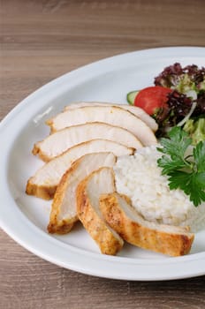 slices of chicken breast with rice and vegetable salad