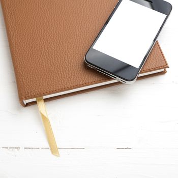 cellphone on notebook over white table