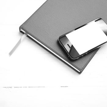 cellphone on notebook over white table black and white tone color style