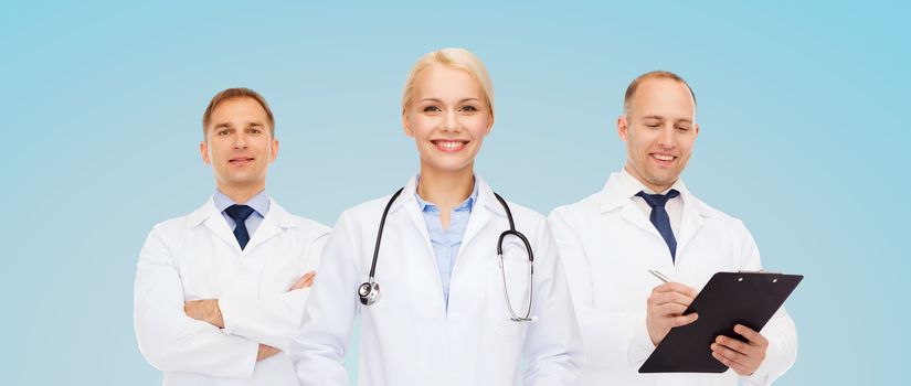 healthcare, people and medicine concept - group of doctors with stethoscope and clipboard over blue background