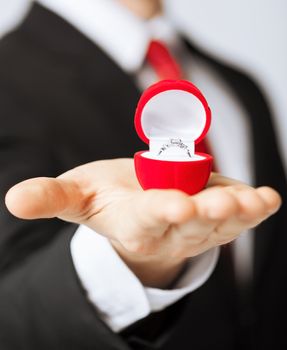 man making proposal with wedding ring in red gift box