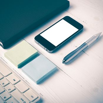 computer and brown notebook with office supplies on white table vintage style