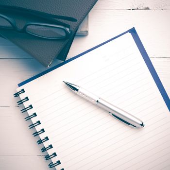 notepad with stack of book on white table view from above vintage style