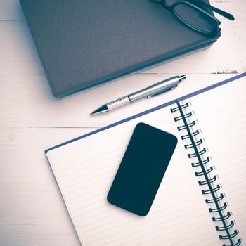 notepad with stack of book on white table view from above vintage style