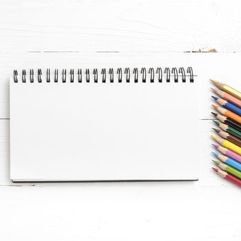 notepad with color pencil on white table view from above