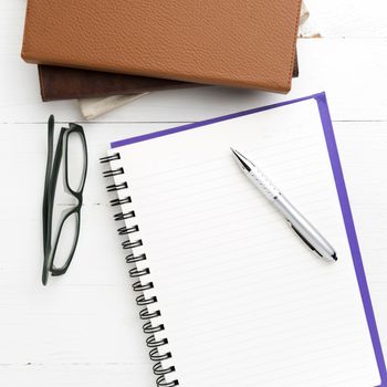 notepad with stack of book on white table view from above