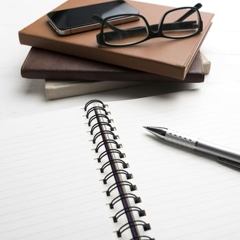 notepad with stack of book on white table