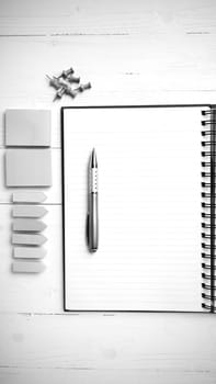 notepad with office supplies on white table view from above black and white tone color style