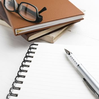 notepad with stack of book on white table