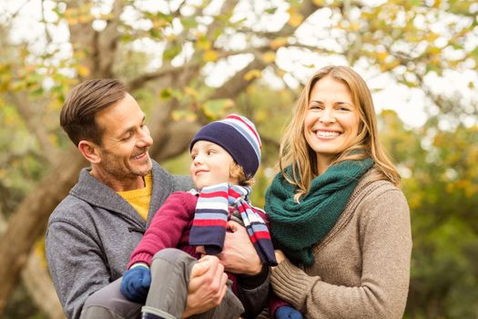 Smiling young couple with little boy posing on an autumns day