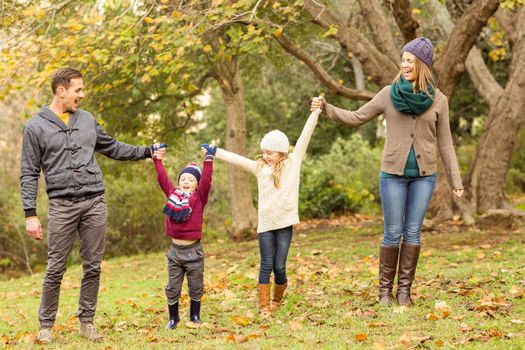 Smiling young family raising their hands on an autumns day