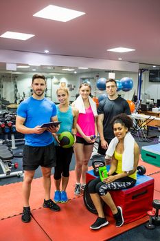 Fit people smiling at camera in weights room at the gym