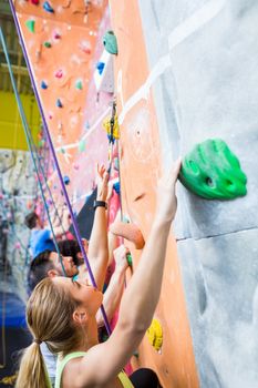 Fit people rock climbing indoors at the gym