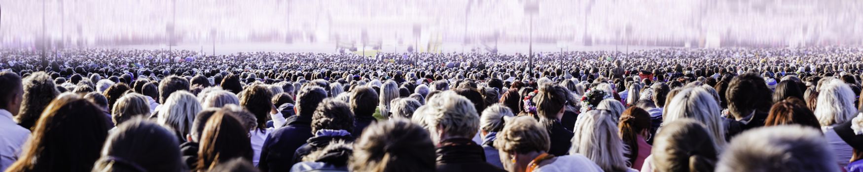 Panoramic photo of large crowd of people. Slow shutter speed motion blur.
