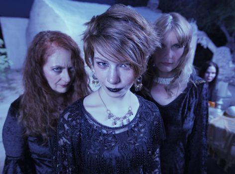 Three beautiful women in black standing together outdoors