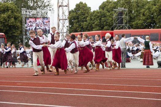 RIGA, LATVIA - JULY 11, 2015: Dancers in traditional costumes perform at the Grand Folk dance concert of Latvian Youth Song and Dance Festival in the Daugava Stadium.