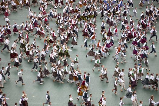 RIGA, LATVIA - JULY 11, 2015: Dancers in traditional costumes perform at the Grand Folk dance concert of Latvian Youth Song and Dance Festival in the Daugava Stadium.