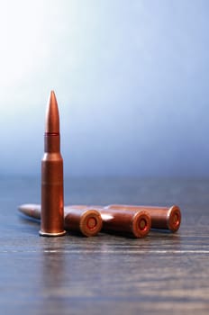 Few rifle cartridges on wooden surface against gray background