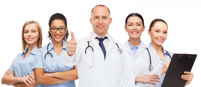medicine, profession, teamwork and healthcare concept - international group of smiling medics or doctors with clipboard and stethoscopes with showing thumbs up over white background