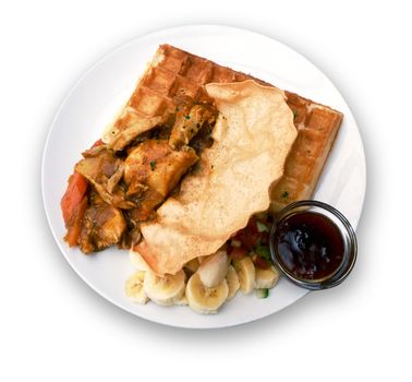 chicken curry on a waffle served with a side of chutney, sambals and bananas