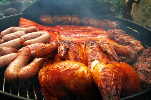 mixture of meat on a barbecue grill almost cooked