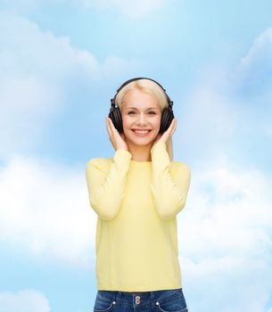 music and technology concept - smiling young woman listening to music with headphones