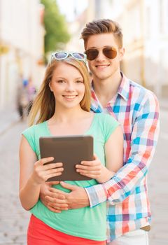 travel, vacation, technology and friendship concept - smiling couple with tablet pc computer in city