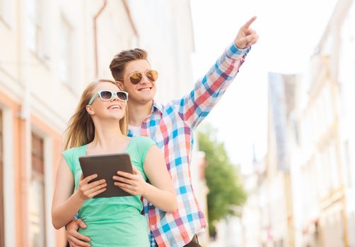 travel, vacation, technology and friendship concept - smiling couple with tablet pc computer in city