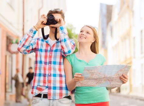 travel, vacation, technology and friendship concept - smiling couple with map and photo camera exploring city