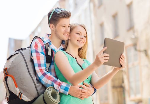 travel, vacation, technology and friendship concept - smiling couple with tablet pc and backpack in city