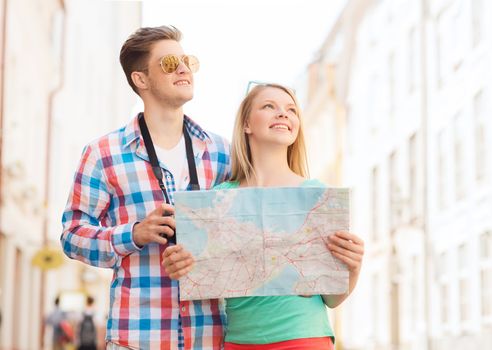 travel, vacation, technology and friendship concept - smiling couple with map and photo camera exploring city