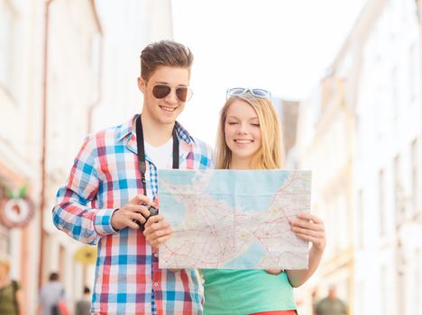 travel, vacation, technology and friendship concept - smiling couple with map and photo camera exploring city