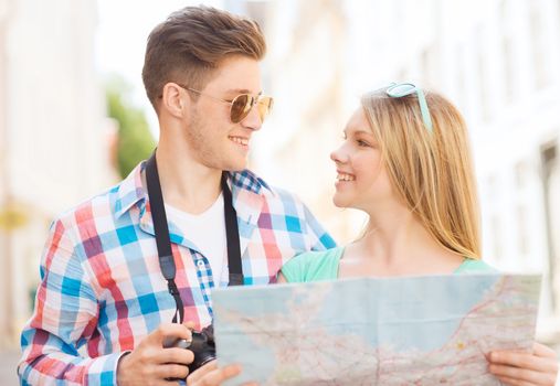 travel, vacation, technology and friendship concept - smiling couple with map and photo camera exploring city