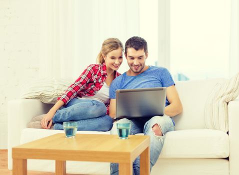 home, technology and relationships concept - smiling couple with laptop computer at home