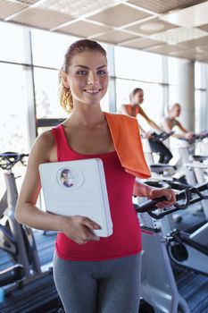 sport, fitness, slimming and people concept - smiling woman with scales and towel in gym