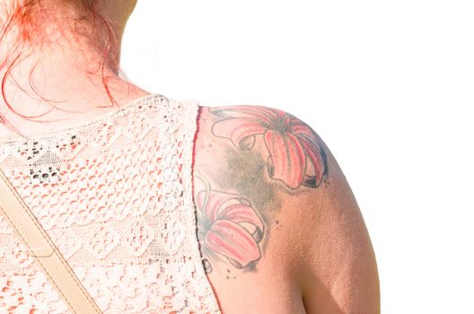 Young Woman with red hair with flowers tattoo on her right shoulder blade. Image isolated.