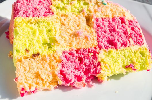 Delicious colorful checkered birthday cake. Cake on white plate.