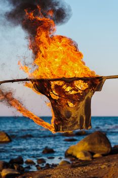T-shirt on a rope in flame on a seashore