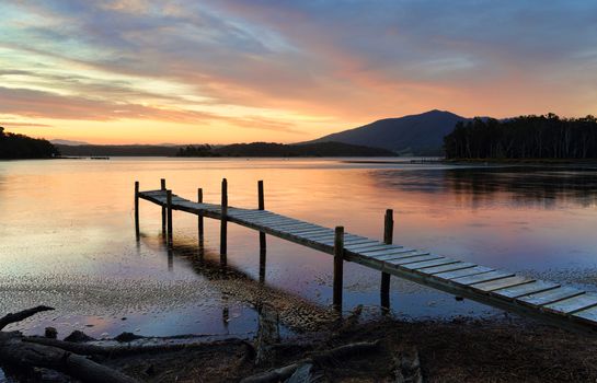 This old rickety timber plank jetty juts out into Wallaga Lake, the largest lake in southern NSW.  The sunset beyond painting the sky and colouring the tranquil waters in soft hues of red and blue.  Mt Gulaga rises in the distance and Merriman Island lies approximately 250 metres offshore and is restricted due to being important aboriginal sacred site.