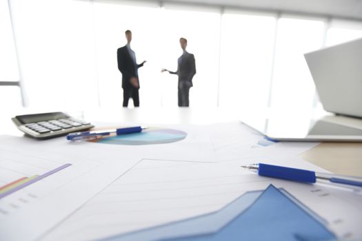 Financial reports, calculator and laptop on table in office