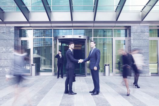 Business people shaking hands, finishing up a meeting outside office